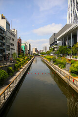 City canal with modern buildings and greenery in Japan.