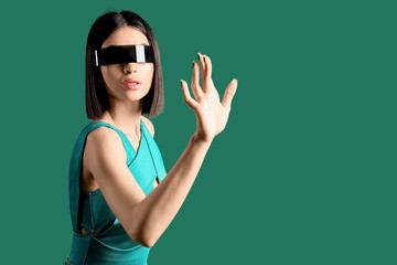 Attractive young woman in VR glasses using virtual screen on green background