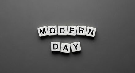Obraz premium The words Modern Day spelled out with white letter tiles on a simple dark grey or black background.