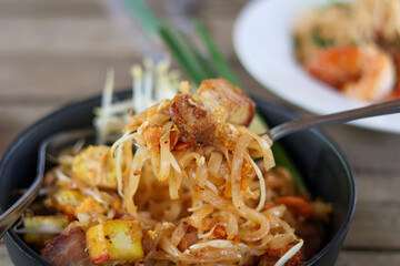 Close Up view Use a spoon to scoop up the Pad Thai with Crispy Pork Belly (Pad Thai Moo Krob) in plat. Popular Thai food in Thailand