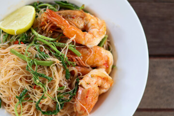 Close Up and Top view of Stir-fried Vermicelli with Water Mimosa with shrimps in plate served on half a plate on wooden background