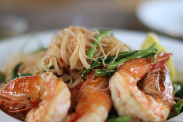 Side view of Stir-fried Vermicelli with Water Mimosa with shrimps in plate on wooden background. Close Up