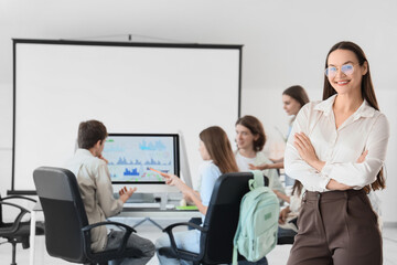 Female teacher and students studying at school computer lab