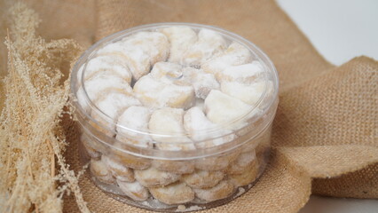 Homemade Putri Salju cookies coated in powdered sugar, stored in a transparent jar. Shot on a clean...