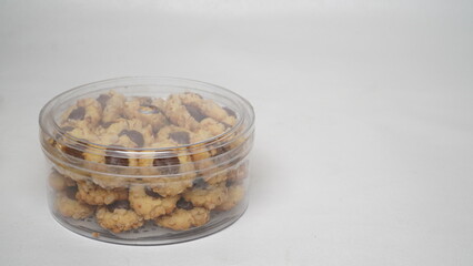 Homemade chocolate thumbprint cookies with peanut sprinkles arranged in a clear plastic jar, isolated on a clean white background. Perfect for dessert packaging mockups or food blogs