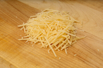 Pile of Grated Parmesan Cheese on Wooden Cutting Board
