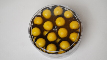 Top view of nastar cookies served in a clear plastic jar and placed on a white surface lined with burlap.