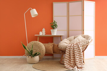 Interior of stylish living room with white lamp, cocoon chair and folding screen