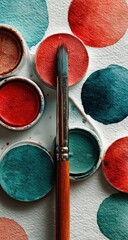 Paintbrush rests on palette of watercolor paints