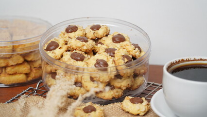 Homemade chocolate thumbprint cookies with peanut sprinkles and with hot black coffee, isolated on a clean white background. 