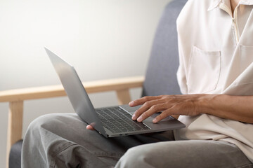 Productive Moment. Young man typing on laptop while seated at home.