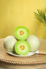 Fresh Jade Melon and Mushroom Melon Halves on Plate with Palm Leaf Shadow