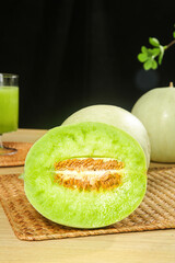 Fresh Jade Green Honeydew Melon Cut in Half Showing Sweet Juicy Flesh and Seeds on Wooden Kitchen...