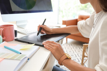 Fototapeta premium Female graphic designer working at table in office, closeup