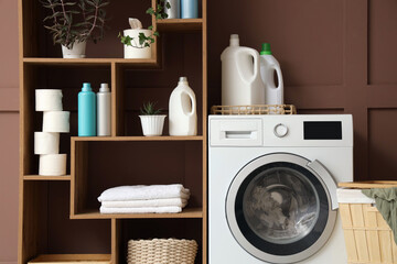 Washing machine with detergents near brown wall in laundry room