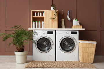 Interior of laundry room with washing machines, basket and plants