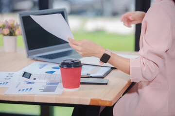 Asian businesswoman wearing glasses and pink suit is working in the office. She is very excited and...