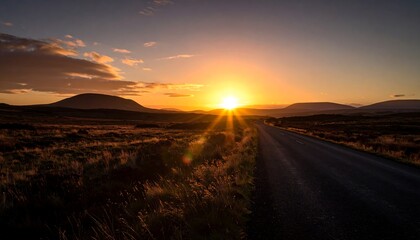 Scenic desert highway at sunset with mountains in the distance.
