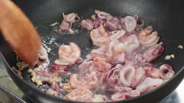 Frying shrimp, squid, and garlic in a pan