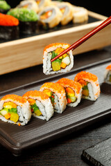 Delicate sushi platter with colorful rolls and chopsticks on wooden board - Japanese cuisine dining experience