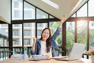 Asian businesswoman is working in office. She is very excited and happy that his business is...