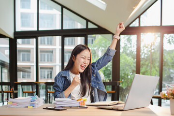 Asian businesswoman is working in office. She is very excited and happy that his business is...