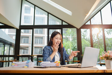 Asian businesswoman is working in office. She is very excited and happy that his business is...