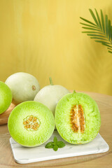 Fresh Sweet Melons Cut in Half on Marble Board with Palm Leaf Shadow and Yellow Background