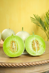 Fresh Green Honeydew Melons Cut in Half on Wooden Board with Palm Leaves