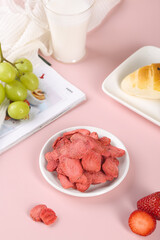 Freeze-dried strawberry snacks with fresh fruit and milk on pink background