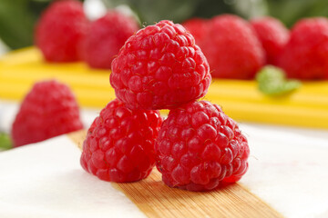 Fresh Red Raspberries on Wood with Shallow Depth of Field and Colorful Fruit Background