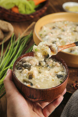 Delicious Homemade Egg Porridge in Wooden Bowl - Healthy Breakfast Comfort Food with Fresh Herbs and Vegetables