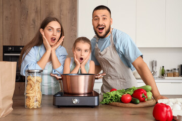 Surprised parents with their little daughter cooking soup in kitchen