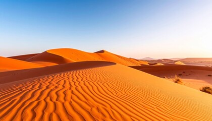 Sunset over the vast, arid orange landscape of the Sahara desert, with wind-swept sand dunes stretching to the horizon