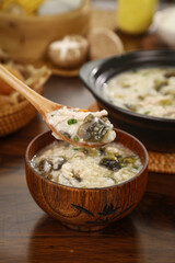 Traditional Chinese breakfast porridge with eggs and seaweed in wooden bowl