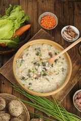 Traditional Asian Congee Rice Porridge Breakfast with Mushrooms and Vegetables on Wooden Table