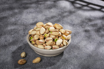 Fresh Salted Pistachios in White Bowl - Healthy Daily Snack Nuts on Gray Background