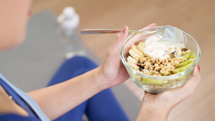 Adult hands holding healthy granola yogurt fruit bowl for nutritious breakfast at home promoting...