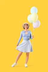 Beautiful woman with balloons on yellow background