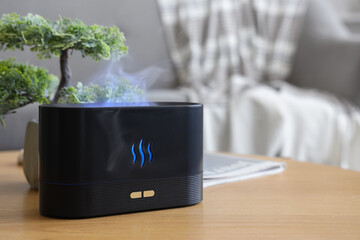 Air humidifier with bonsai tree on table in living room, closeup