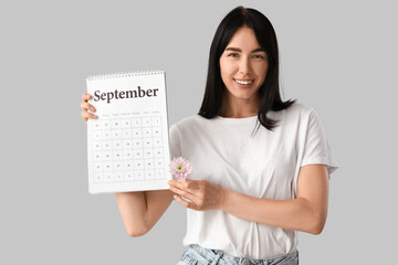 Young woman with calendar and flower on light background. Menstruation concept