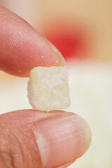 Hand Holding White Crystalline Winter Melon Candy Cube with Sugar Coating
