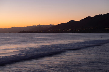 Sunset waves crash along the rugged coast of Pismo Beach, California, USA.