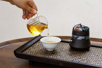 Traditional Chinese Tea Ceremony Pouring Golden Puerh Tea from Glass Teapot into Porcelain Cup on...