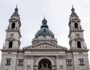 Fototapeta premium Budapest, Hungary – Architectural detail of St. Stephen’s Basilica, showcasing its neoclassical façade, ornate columns, sculpted tympanum, and twin bell towers. A symbol of faith and grandeur.