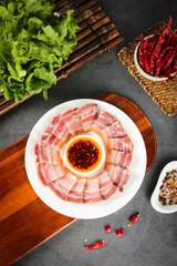 Sliced Smoked Pork Bacon on Plate with Chili Peppers and Fresh Lettuce on Old Wood Table