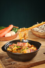Asian Bacon Eggplant Stew with Noodles in Black Bowl - Chopsticks Lifting Food