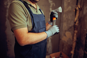Construction Worker Holding a Demolition Axe on Worksite. Skillful contractor with proper tools for...