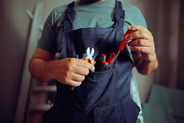 Construction Worker with a Pocket Full of Tools in his Overalls. Handymen having specific tools for...