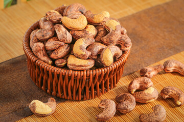 Roasted Cashew Nuts in Wicker Basket on Wooden Background